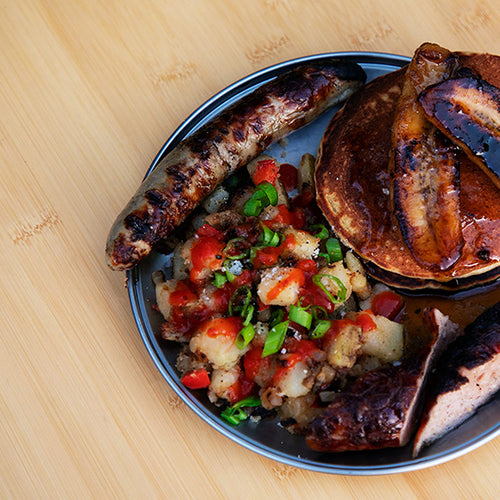 A Titanium Plate on a Single Action Table filled with sausage, hash browns, and sourdough pancakes topped with caramelized bananas.