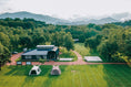 Daytime view of the campfield, set among lush forest with open fields for social campsites.