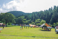 A closer view of the campfield with several campsites set up and the rolling mountains behind them.