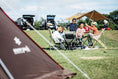 Campsites set up in the open field portion of the Osaka campfield. Kids are gathered together playing in the center of campsites.